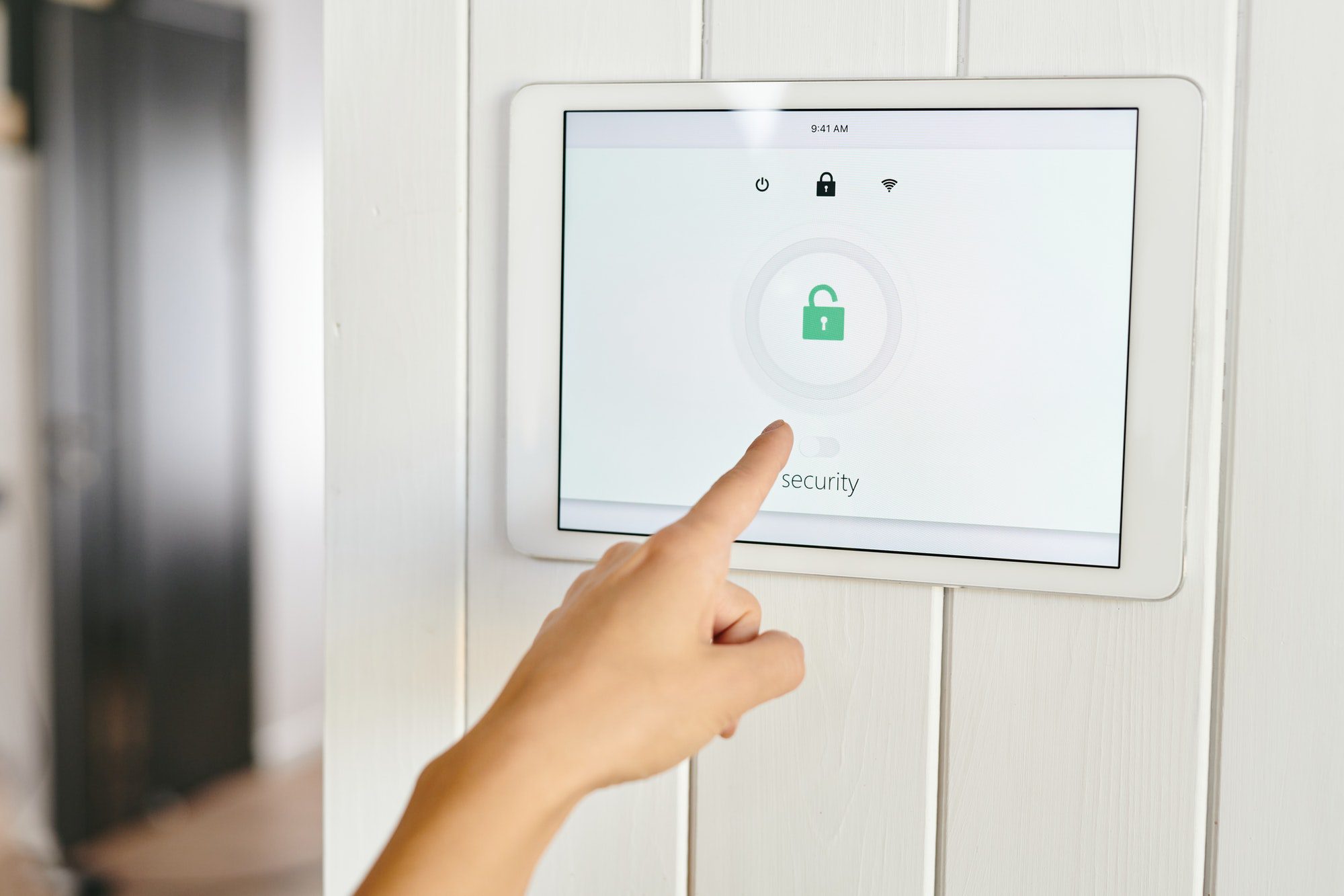 A hand pointing at panel of home security appliance
