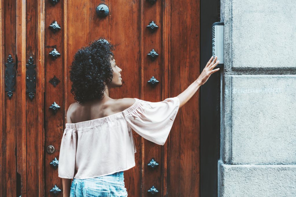 Biracial woman using a door intercom