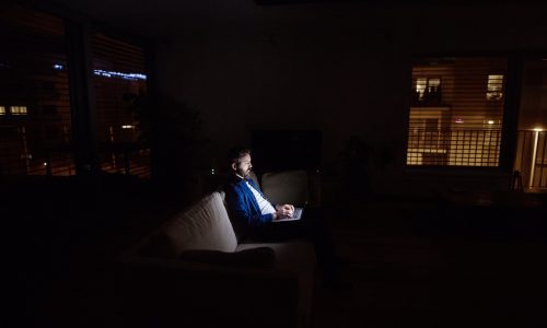 A man working on a laptop at home at night.