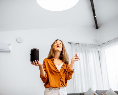 Woman controlling light with a smart speaker at home Woman controlling light with a smart speaker at home